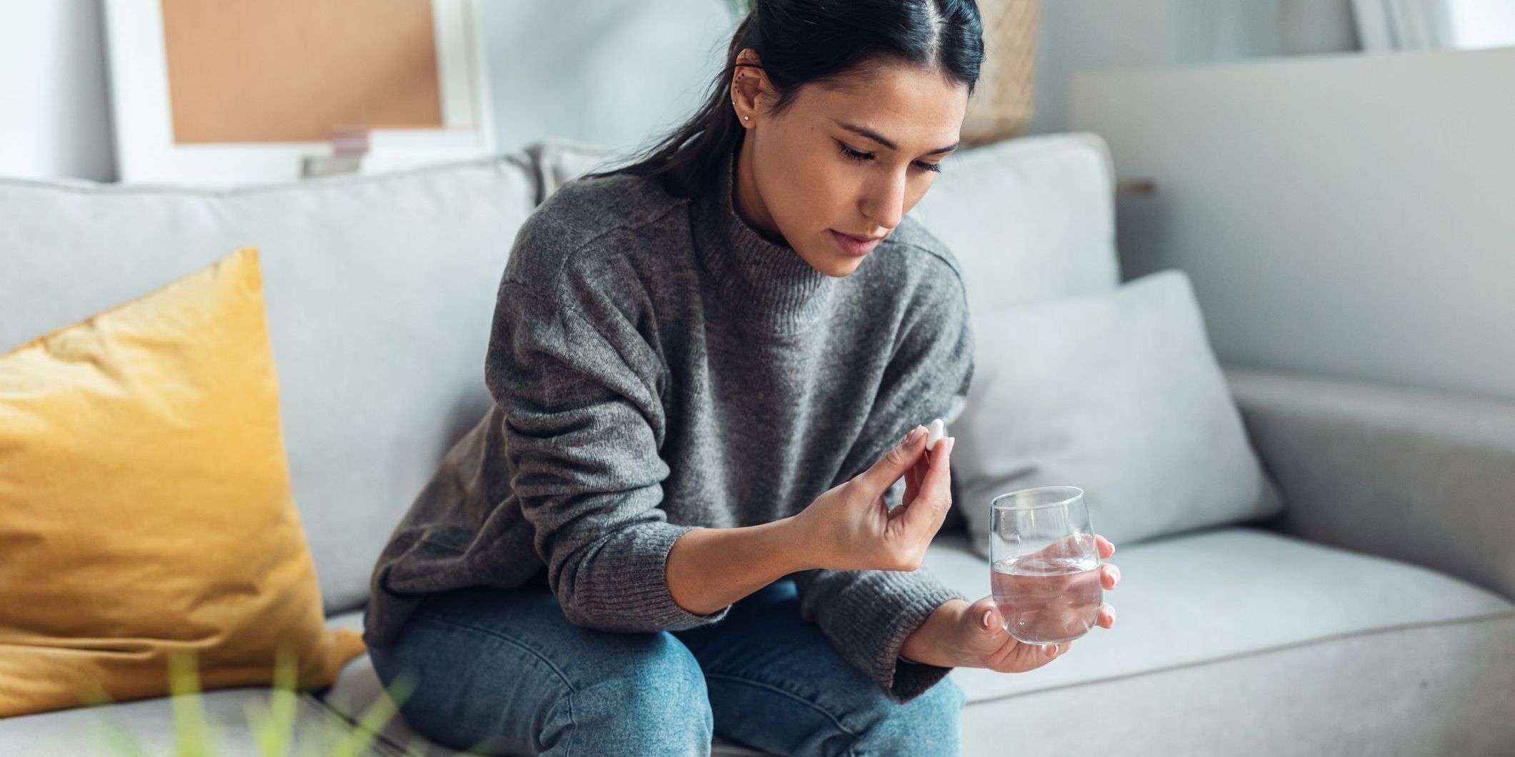 woman taking medication on a couch - addictive personality